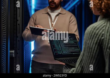IT professionals working and discussing over data on laptop in server room Stock Photo