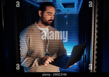 Young IT professional using laptop and working in data center Stock Photo
