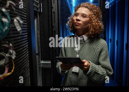 Young IT engineer examining supercomputer equipment and holding tablet PC in data center Stock Photo