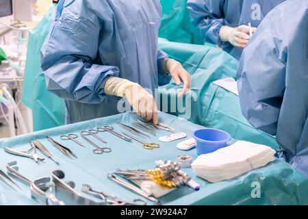 Nurse holding surgical tool with surgeons performing surgery on patient in emergency room Stock Photo