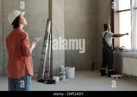 Engineer holding tablet PC with coworker looking through window at construction site Stock Photo
