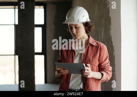 Engineer wearing hardhat and using tablet PC at construction site Stock Photo