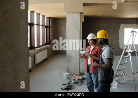 Engineer using tablet PC and planning with coworker at construction site Stock Photo
