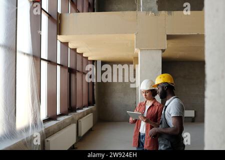 Engineer using tablet PC and discussing with coworker at construction site Stock Photo