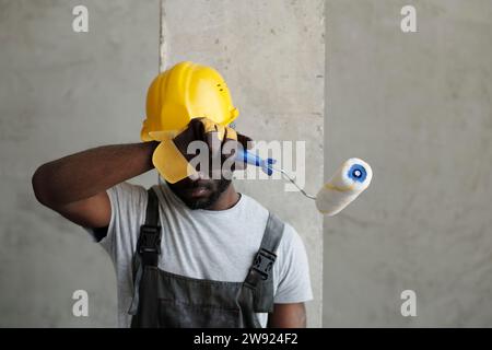Tired construction worker wiping sweat at site Stock Photo