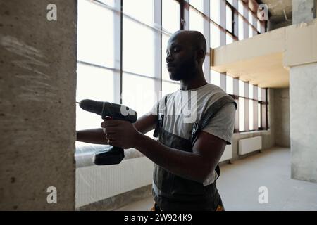 Construction worker drilling wall at site Stock Photo