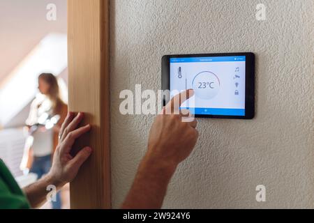 Man adjusting temperature through home automation app on tablet PC Stock Photo