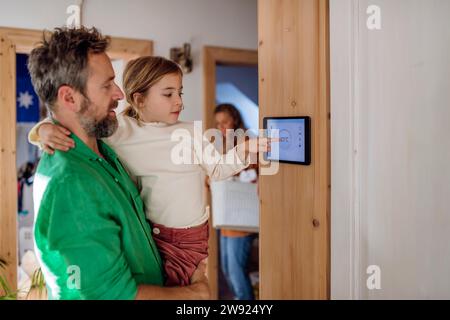 Daughter adjusting temperature through app on tablet PC with father at home Stock Photo
