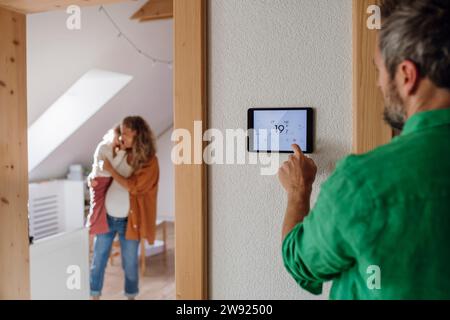 Man controlling temperature through home automation app on tablet PC Stock Photo