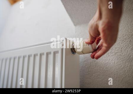 Hand of man adjusting radiator near wall Stock Photo