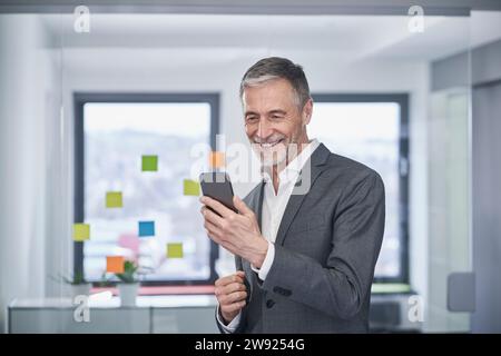 Happy senior businessman using mobile phone Stock Photo