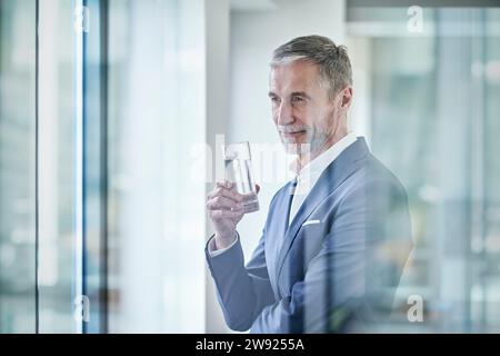 Thoughtful businessman holding glass of water Stock Photo