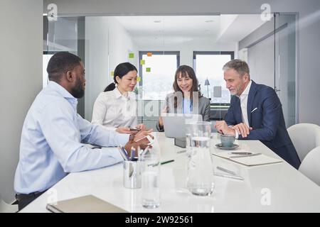 Smiling businessmen and businesswomen having discussion over laptop Stock Photo