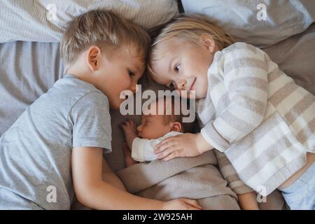 Newborn baby boy sleeping near siblings lying in bed Stock Photo