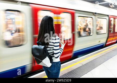 Woman with backpack standing near subway at station Stock Photo
