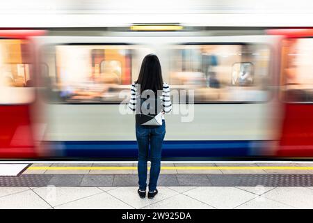 Woman with backpack standing in front of subway at station Stock Photo
