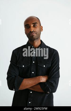 Serious man standing with arms crossed against white background Stock Photo
