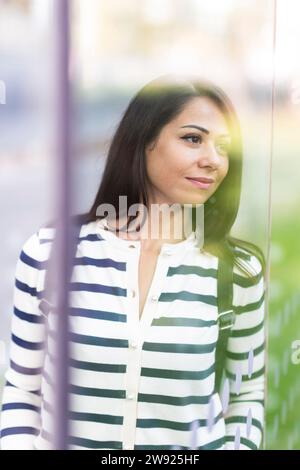 Thoughtful woman looking through glass Stock Photo