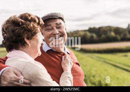 Happy senior couple spending leisure time at field on sunny day Stock Photo