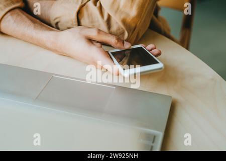 Young man text messaging through phone on table at home Stock Photo