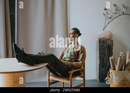 Young man sitting with feet up on table relaxing at home Stock Photo