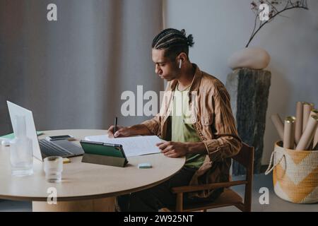 Young man writing in book and studying at home Stock Photo