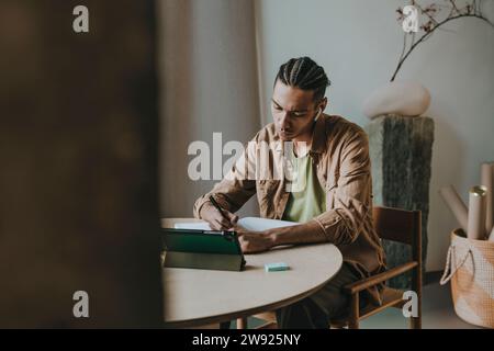 Young man writing and studying at home Stock Photo