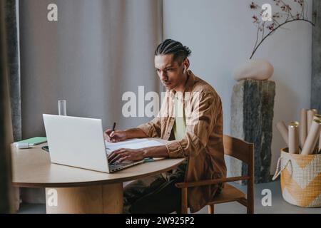 Dedicated young man using laptop learning through online tutorial at home Stock Photo