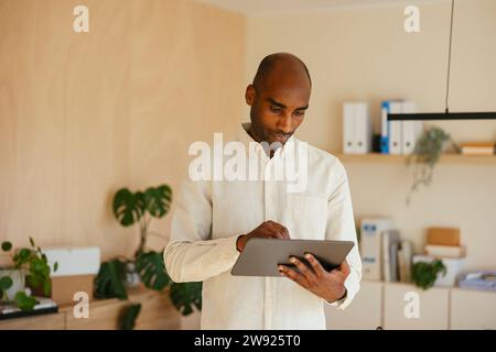 Confident businessman using digital tablet standing at home office Stock Photo