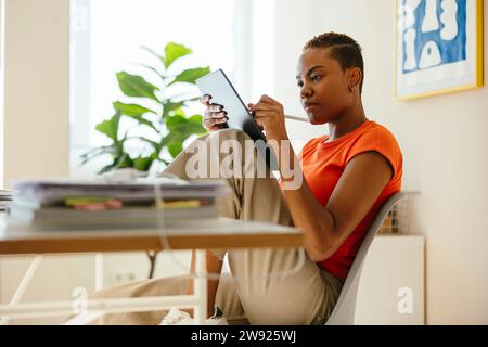Dedicated businesswoman using digital tablet sitting by desk in home office Stock Photo