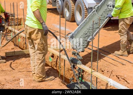 Using concrete vibrator construction worker compacts concrete into trenches for foundation of house Stock Photo