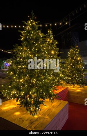 Christmas tree in pot with red decorations and lights outdoors near grey loft building Stock Photo