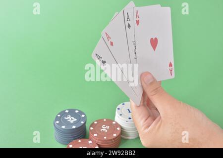 Four aces in a hand with various denomination poker chips on a green felt background, poker cards and chips Stock Photo