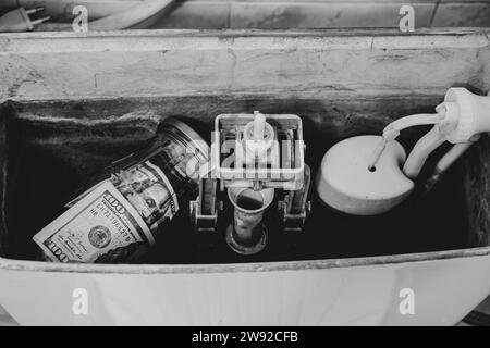 One hundred dollar bills lie in a jar that lies in the toilet tank in the toilet in the apartment, money is hidden in the toilet, savings Stock Photo