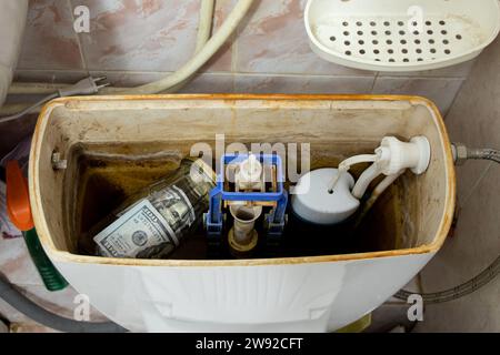 One hundred dollar bills lie in a jar that lies in the toilet tank in the toilet in the apartment, money is hidden in the toilet, savings Stock Photo