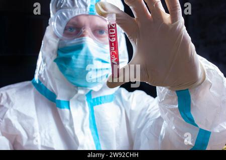 Doctor laboratory assistant in personal protective equipment against coronavirus holds a test tube with blood to perform a test for covid 19 Stock Photo