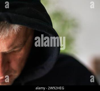 Man looked like hacker in a hood looking at the screen Stock Photo