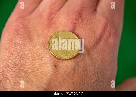 coin face of 50 euro cents on the back of the hand. green background Stock Photo