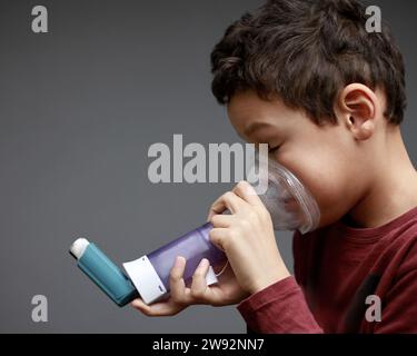 child with flu and inhaler respiratory puff on grey background with ...