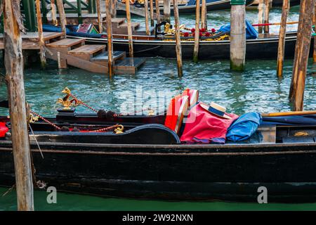 Panama hat on red rug on black gondola at pier in characteristic Venetian image Stock Photo