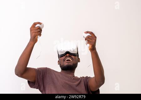Excited Black Man wearing vr headset playing virtual reality game holding controllers. Man playing online games. vr gaming concept Stock Photo