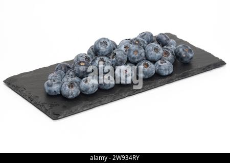 Blueberries on black slate and isolated on white background. Stock Photo