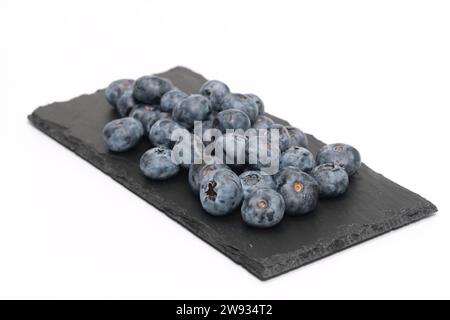 Blueberries on black slate and isolated on white background. Stock Photo