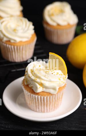 Delicious lemon cupcakes with white cream on black table, closeup Stock Photo