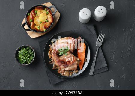 Tasty cooked rabbit meat with vegetables and potato served on black table, flat lay Stock Photo