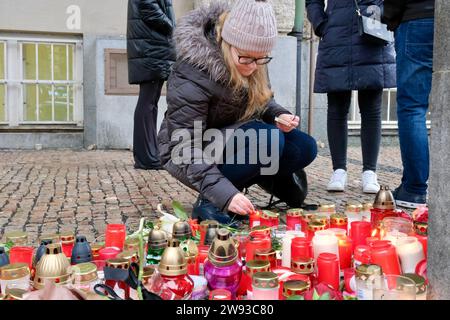 Prague, Czech Republic. 23rd Dec, 2023. A woman lights a candle outside the building of the Faculty of Arts of Charles University in Prague, the Czech Republic, Dec. 23, 2023. The Czech Republic on Saturday mourned the victims of a university shooting in the capital Prague that has left 14 people dead. On Thursday, a 24-year-old student from the faculty shot and killed 14 people before committing suicide. The tragic incident also left 25 others injured, among whom, three were foreigners, according to police. Credit: Deng Yaomin/Xinhua/Alamy Live News Stock Photo
