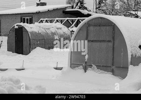 garden in winter, greenhouse covered with snow, trees, garden house and garden accessories, small garden in winter Stock Photo