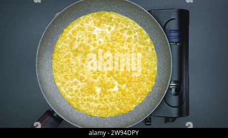 Cooking a Delicious Corn Breakfast on a Portable Gas Stove in a Pan Stock Photo