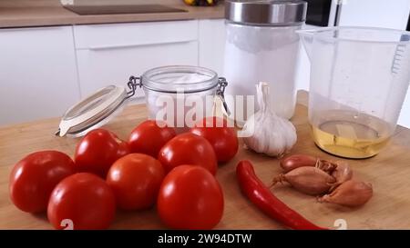 Fresh Tomatoes with Chilies Onion Garlic Flour and Jars Beautifully Arranged on a Wooden Table Stock Photo
