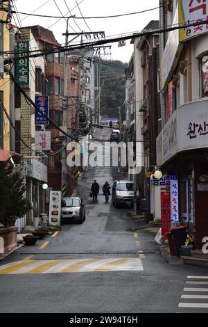 Two people walking down a small alley with a steep incline and overhanging power cables in Seodaemun-gu district Stock Photo